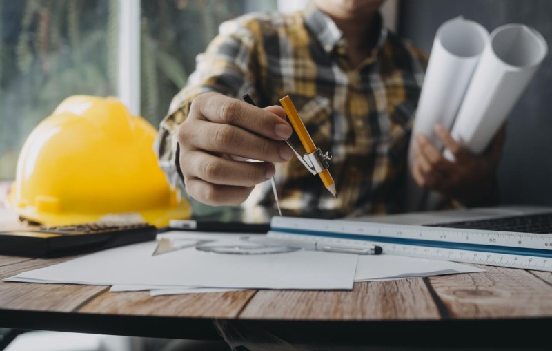 business-hand-working-laptop-with-architectural-project-construction-site-office-desk-office